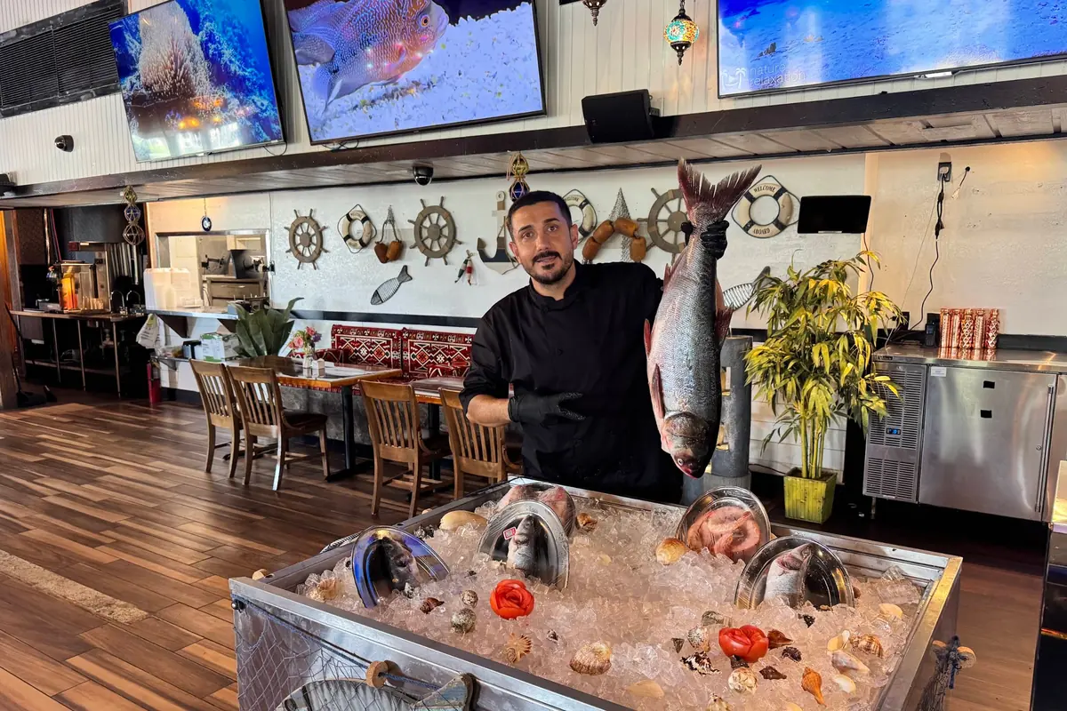 The chef holding the day's fresh fish beside the ice counter